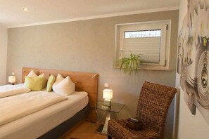 A hotel room with a bed, a glass table, a chair, a window with blinds, and a wall-mounted plant. - Holiday apartment with 3 bedrooms (Zwiesel)