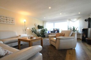 A living room with a sofa, armchair, coffee table, and a fireplace. - Holiday apartment with 3 bedrooms (Zwiesel)
