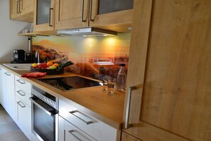 Una cocina con armarios de madera, encimera de acero inoxidable y horno empotrado.