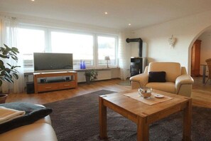 A living room with a sofa, a coffee table, a television, and a fireplace. - Holiday apartment with 3 bedrooms (Zwiesel)