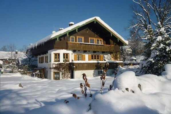 Ein Chalet mit geneigtem Dach, einem Holzbalkon und verschneiter Umgebung.