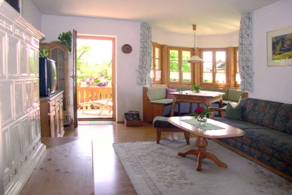 A living room with a sofa, a dining table, and a kitchen area visible through an open door.