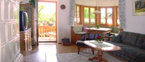 A living room with a sofa, a dining table, and a kitchen area visible through an open door.