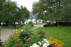 A park with a gravel path, lush green grass, and a variety of flowers. - At Paulfischer right on Lake Chiemsee (Chieming)