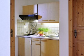 A kitchen with wooden cabinets, a black range hood, a sink, and a potted plant. - At Paulfischer right on Lake Chiemsee (Chieming)