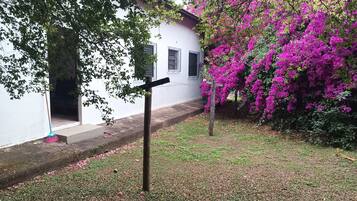 A white building with a paved entrance and a tree with pink flowers.