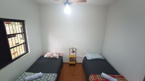 Un alojamiento pequeño y de una sola habitación con dos camas individuales, un ventilador de techo y una ventana con rejas.