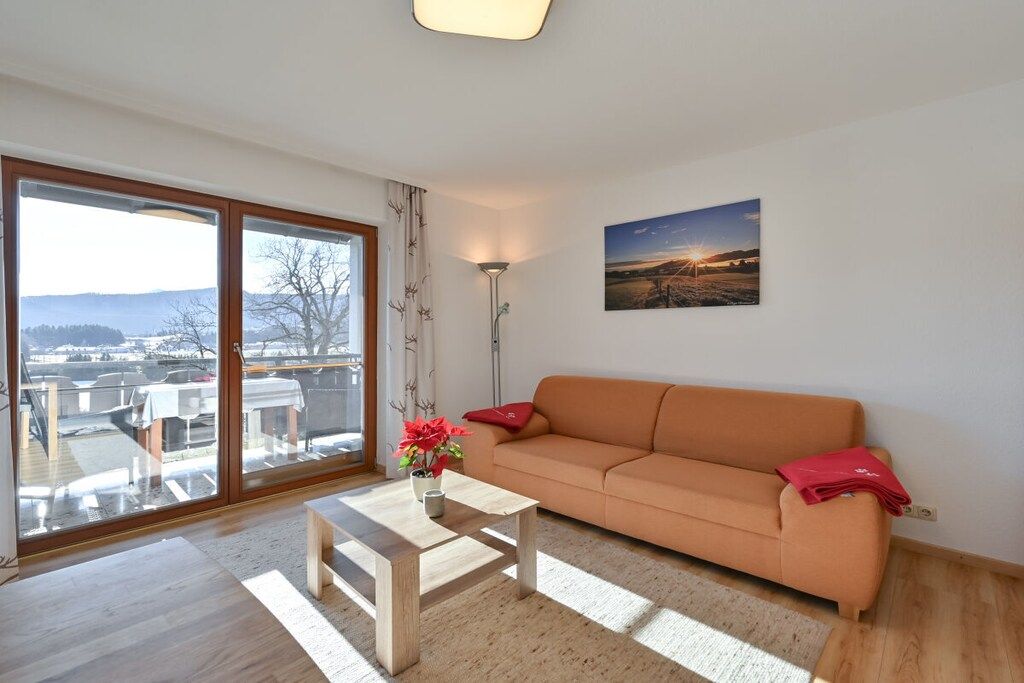 Un salon avec un canapé, une table basse et une vue sur l’extérieur, accessible par une porte-fenêtre coulissante.