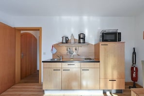 Een kleine keuken met een magnetron, koffiezetapparaat en waterkoker op het aanrecht.