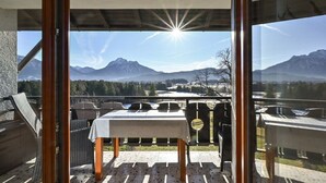 Ein Balkon mit Tisch und Stühlen mit Blick auf eine gebirgige Landschaft.