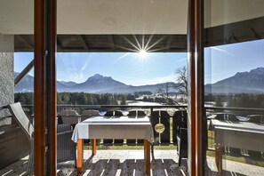Uma varanda com mesa e cadeiras, com vista para uma paisagem montanhosa.