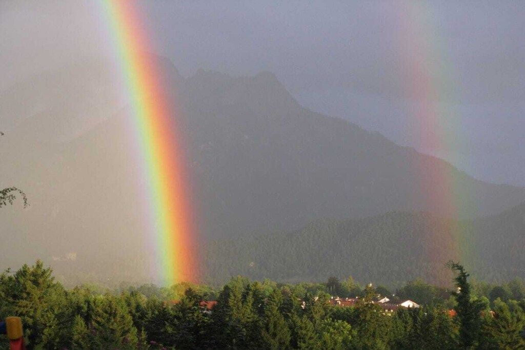 Ein Berg mit einem Regenbogen im Vordergrund.