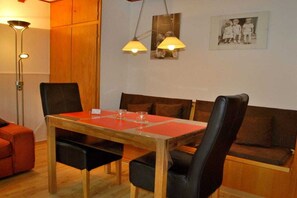 En matplats med ett träbord, svarta stolar och en bänk. Två hänglampor sitter ovanför bordet.