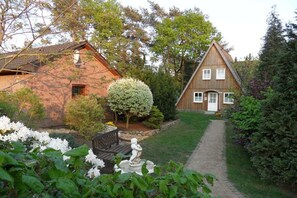 Ett hus byggt av tegel med en trästomme, beläget i en trädgård.