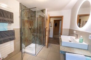A modern bathroom with a glass-enclosed shower, a white sink with a mirror, and a towel rack. - Holiday apartment with 1 bedroom (Übersee)