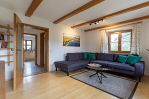 A modern living room with a sectional sofa, a coffee table, and a painting on the wall. - Holiday apartment with 1 bedroom (Übersee)