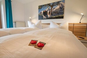 A hotel room with a large bed, a painting of cows on the wall, and a nightstand with a lamp. - Holiday apartment with 1 bedroom (Übersee)