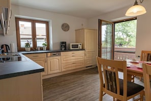 A kitchen with wooden cabinets, a microwave, and a dining area with a table and chairs. - Holiday apartment with 1 bedroom (Übersee)