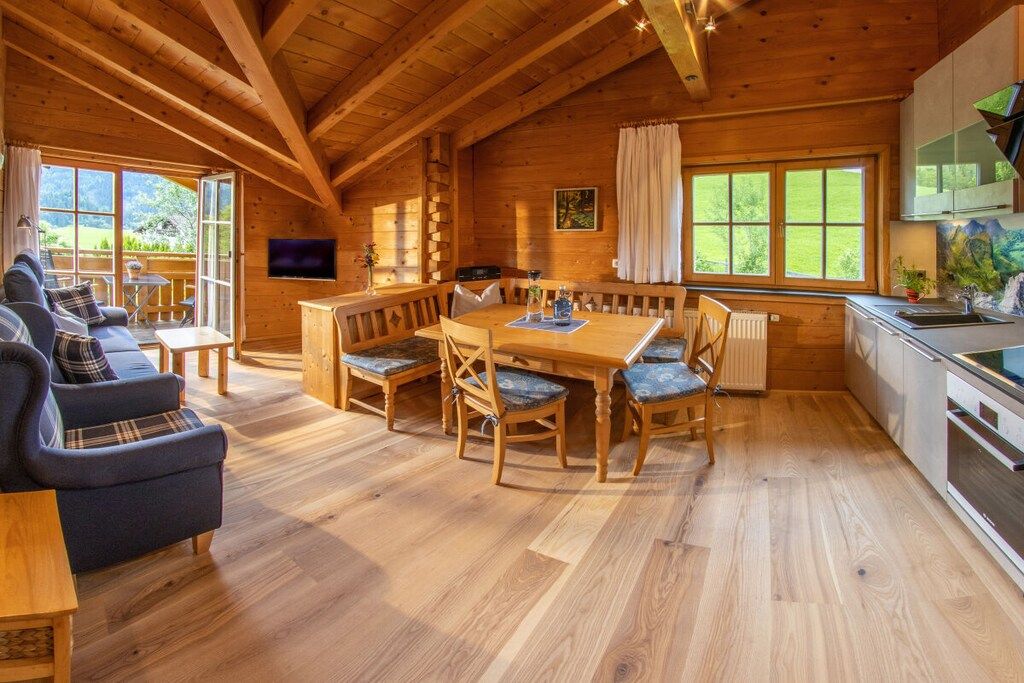 Interior de una cabaña de madera con comedor, sofá y cocina.