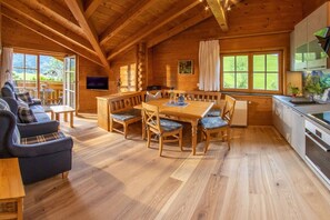 Interior d'una cabana de fusta amb zona de menjador, sofà i cuina.
