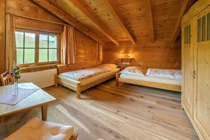 Una cabana de fusta amb dos llits, una taula i una finestra.