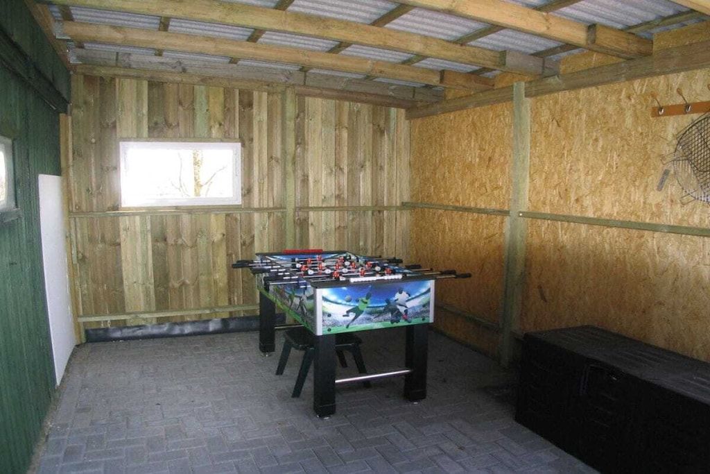 A room with a foosball table, a window, and a wooden wall.