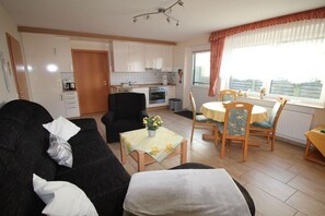 Een knus woongedeelte met een kitchenette, een eethoek en een bank.
