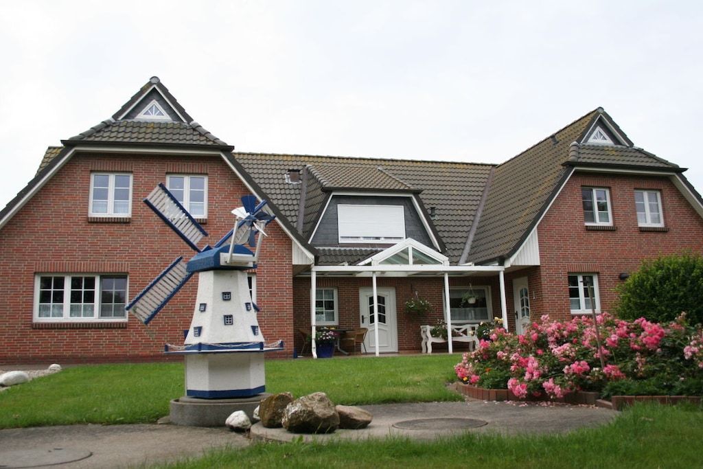 A two-story brick house with a windmill in the front yard.