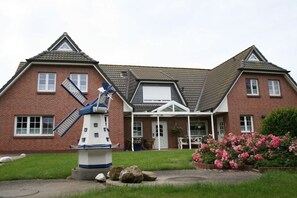 Een herenhuis van baksteen met een windmolen in de voortuin.