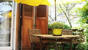 A wooden door with shutters, a table with a potted plant, and a yellow umbrella. - Holiday apartment with 1 bedroom (Gummersbach - Lieberhausen)