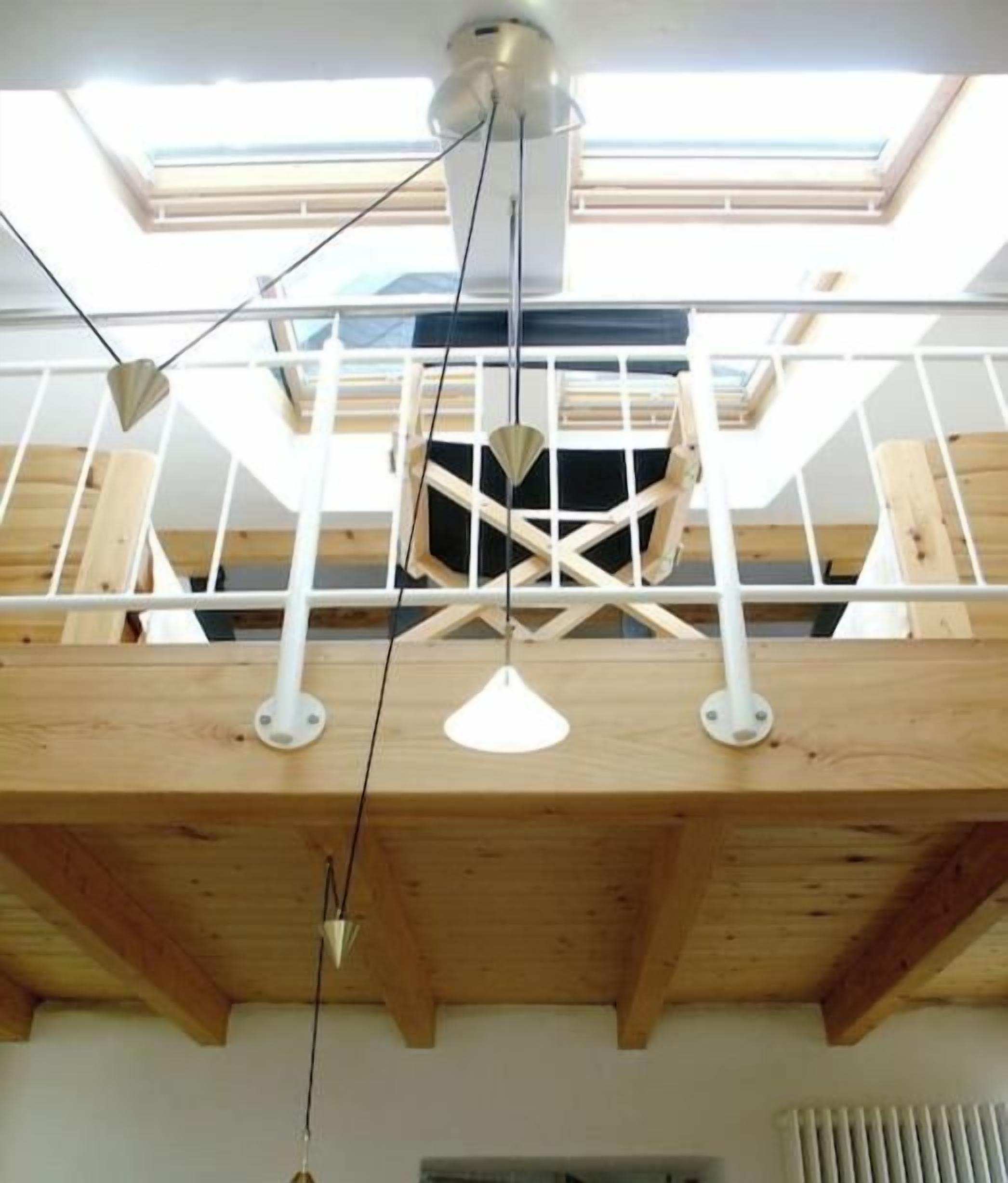 Un plafond en bois agrémenté d’une lucarne, de poutres apparentes et de luminaires suspendus.