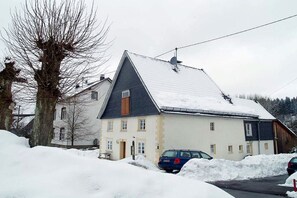 A two-story building with a sloped roof, parked cars, and snow on the ground. - Holiday apartment with 1 bedroom (Gummersbach - Lieberhausen)
