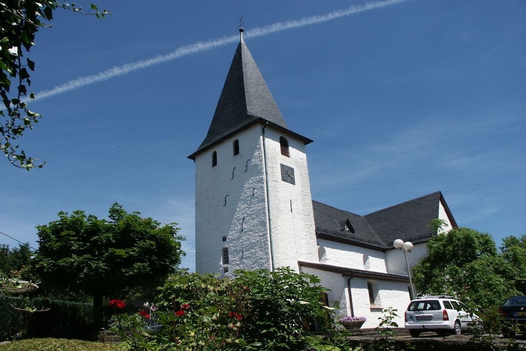 Une église dotée d’un haut clocher et d’une façade blanche.