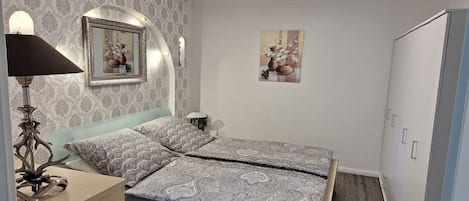 A bedroom with a bed, a bedside lamp, a mirror, and a wardrobe.