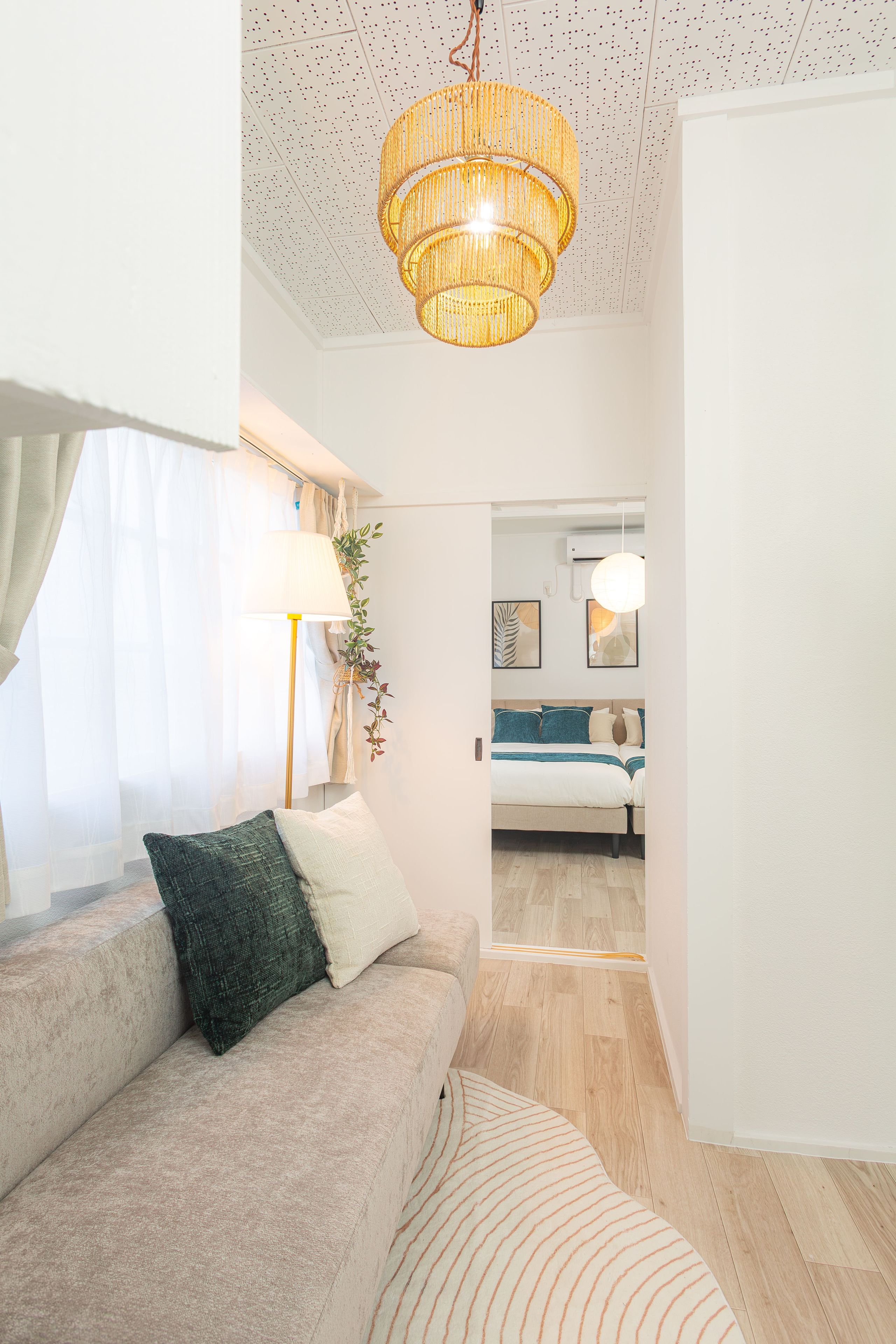A modern living room with a sofa, a lamp, and a hanging light fixture.