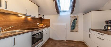 Een moderne keuken met witte kastjes, houten aanrecht en een dakraam.