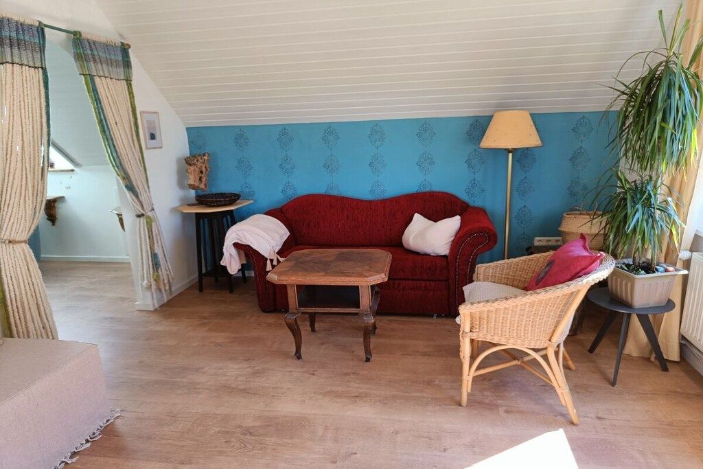 Un salon chaleureux avec un canapé rouge, une table basse en bois et un fauteuil en osier.