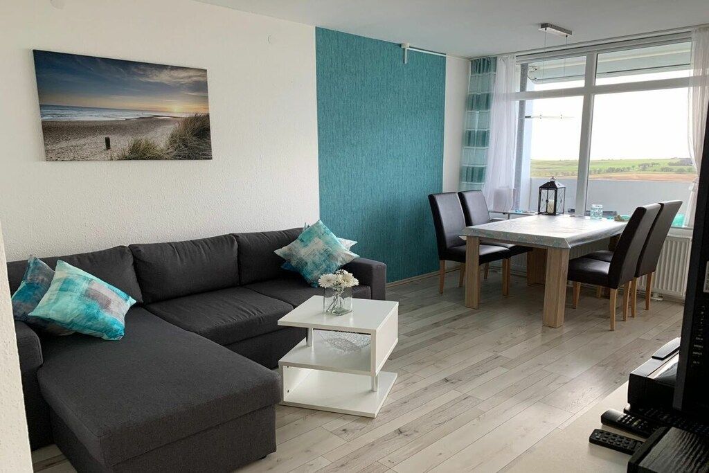Een moderne woonkamer met een bank, salontafel en een eethoek.