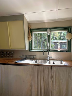 A kitchen with a window, a sink, and a wooden countertop.