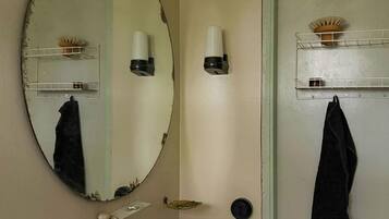 A bathroom with a round mirror, a white sink, and a towel rack.