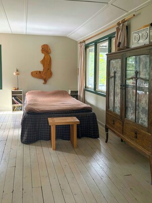 Ein Schlafzimmer mit einem Bett, einem Holzschrank, einem kleinen Tisch und einer an der Wand befestigten Holzskulptur.