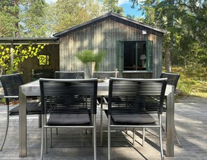 Ein Essbereich im Freien mit einem Holzgebäude, Metallstühlen und einem Tisch.