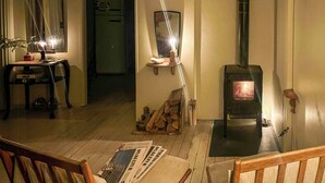 A cozy living room with a wooden table, chairs, a fireplace, and a mirror on the wall.