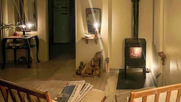 Een knusse woonkamer met een houten tafel, stoelen, een open haard en een spiegel aan de muur.