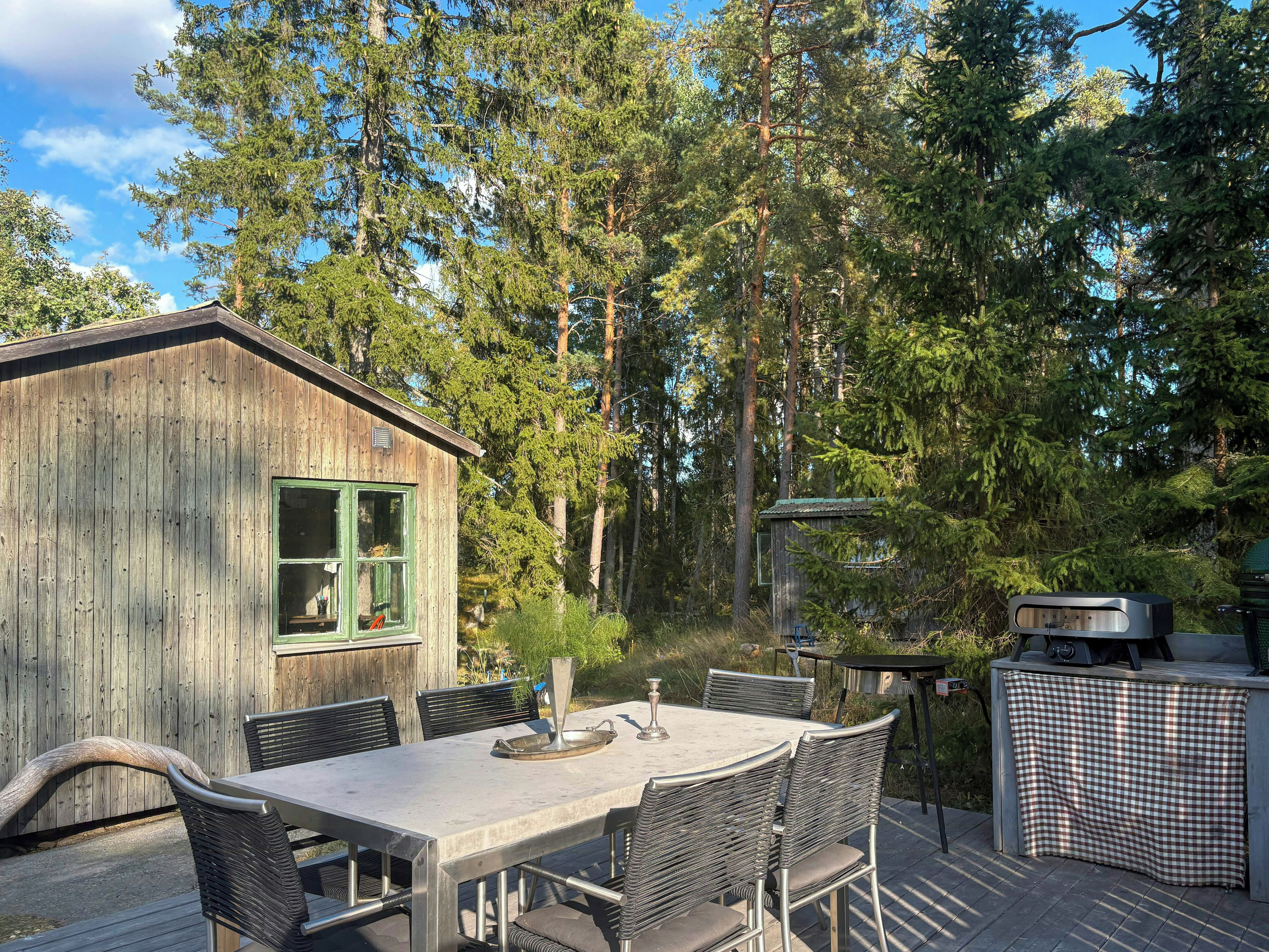 Une cabane en bois avec une table et des chaises, entourée de grands arbres.