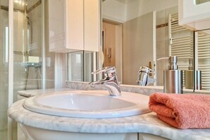 A bathroom with a white sink, chrome faucet, and a glass shower enclosure. - Holiday apartment with 1 bedroom (Fehmarn)