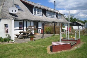 A traditional building with a sloped roof, a wooden fence, and a picnic table in the yard. - Nydamsgaard "hus lille rede" (Faaborg \/ Bojden)