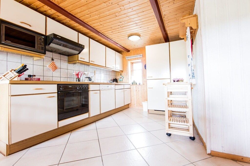 A kitchen with white cabinets, a microwave, stove, and a small refrigerator.