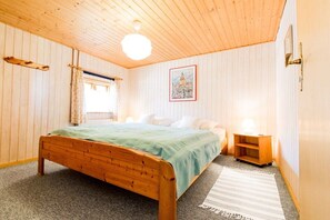 Ein Zimmer mit einem hölzernen Bett, einem Nachttisch, einer Lampe und einem gerahmten Bild an der Wand.