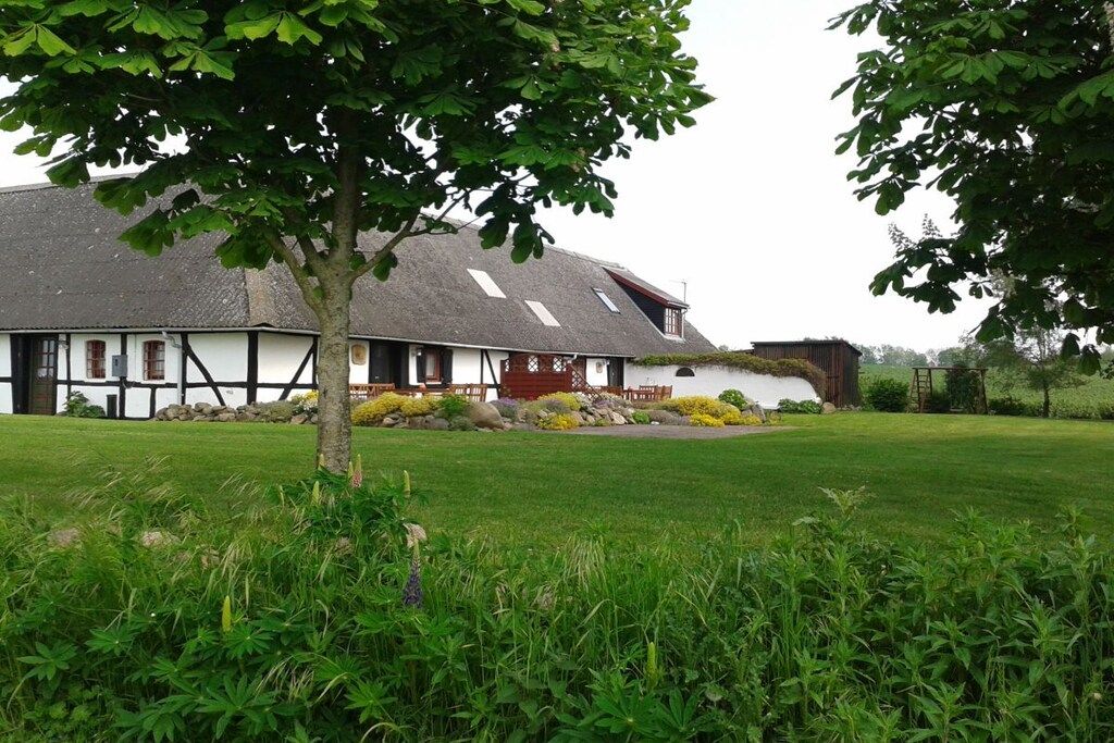 A traditional building with a sloped roof, surrounded by a well-maintained lawn and a tree in the foreground.